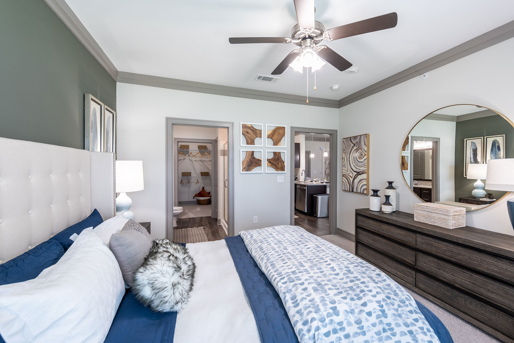 staged bedroom with ceiling fan, private bathroom, and walk in closet